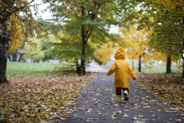 Ett barn i en regnrock för en promenad utanför — Stockfoto