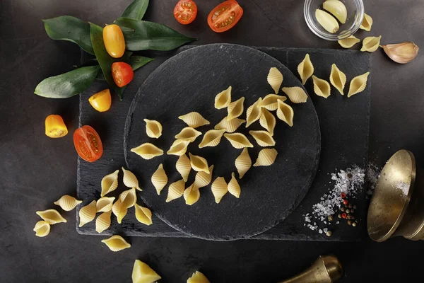 Nudelschalen auf schwarzem Stein. Tomaten und Lorbeerblätter mit Pallspi — Stockfoto