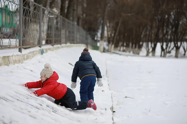 Barn leker ute på vintern. Snö spel på gatan. — Stockfoto