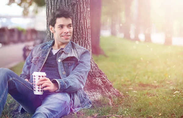 A young man walks in the park at lunch time. A man is on a walk