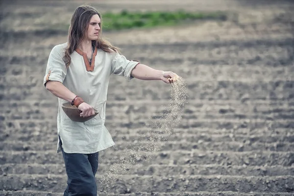 A young peasant sows the field with grain — Stock Photo, Image