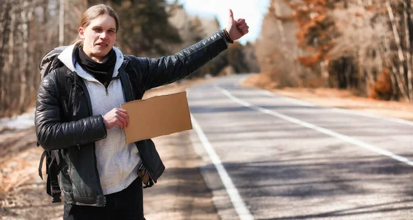 Młody człowiek jest autostop w całym kraju. Człowiek jest trudny — Zdjęcie stockowe