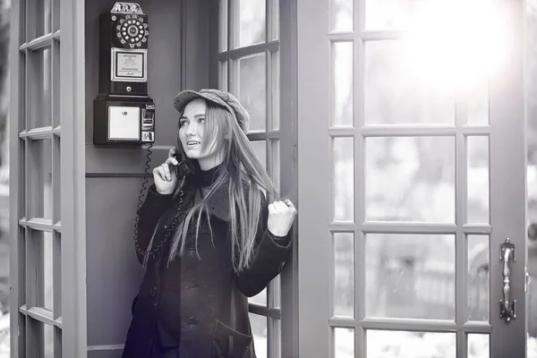 Hermosa jovencita en una cabina telefónica. La chica está hablando en th —  Fotos de Stock