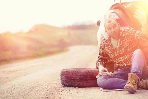 Man is sitting on the road by the car — Stock Photo, Image