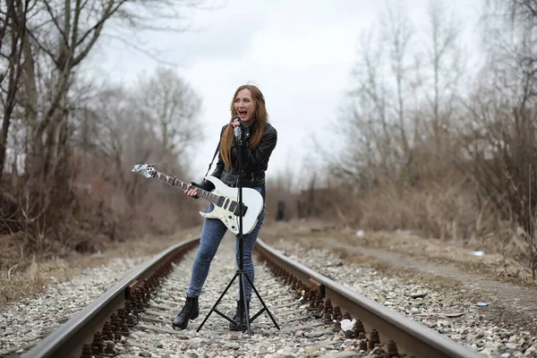 Een rock muzikant meisje in een leren jas met een gitaar — Stockfoto