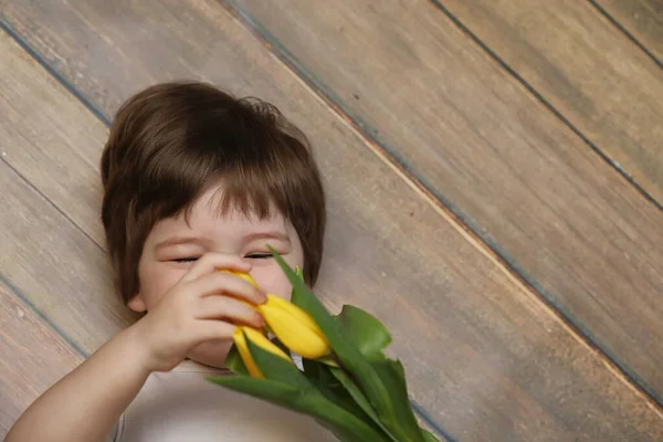 Un niño pequeño con un ramo de tulipanes amarillos. Un chico con un regalo — Foto de Stock
