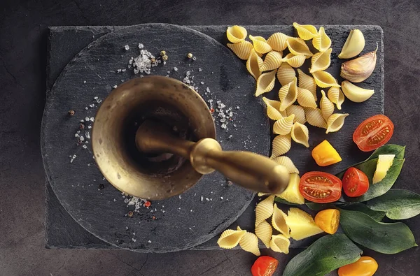 Cáscaras de pasta sobre piedra negra. Tomates y hojas de laurel con allspi — Foto de Stock