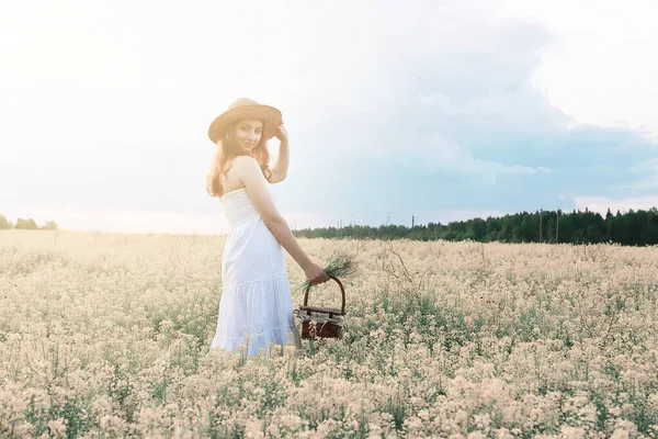 Flicka i vit klänning i ett fält av gula blommor blommar — Stockfoto