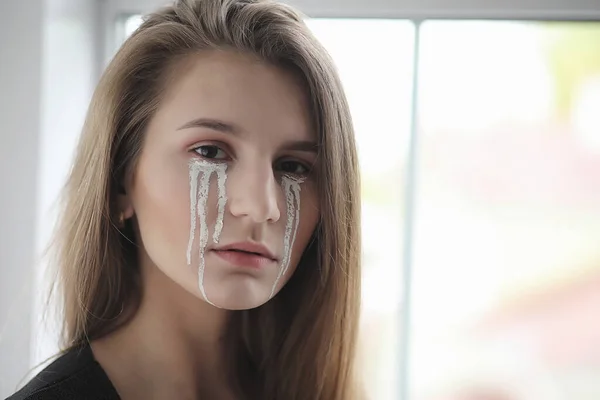 Beautiful girl with tears in her eyes. Young girl with painted t