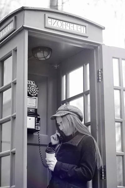 Hermosa jovencita en una cabina telefónica. La chica está hablando en th — Foto de Stock