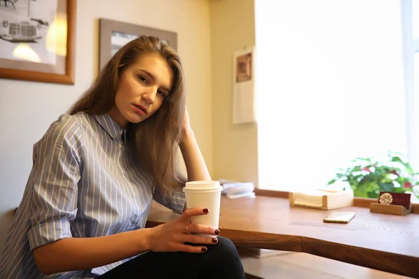 Chica con café. Joven hermosa chica está sentado en un café y — Foto de Stock