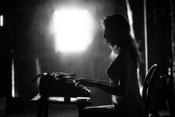 A girl prints on an old typewriter — Stock Photo, Image