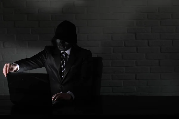 Hacker con máscara negra y capucha en la mesa — Foto de Stock