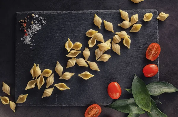 Nudelschalen auf schwarzem Stein. Tomaten und Lorbeerblätter mit Pallspi — Stockfoto