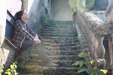 adam eski bina terk edilmiş merdivende oturup