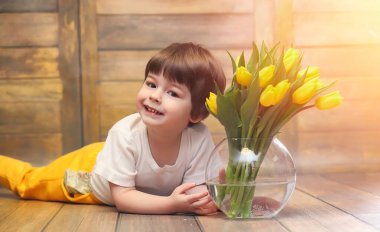 Bir buket Sarı laleler ile küçük bir çocuk. Bir çocuk bir hediye ile