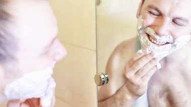 Bir adam sabahları banyoda tıraş oluyor.