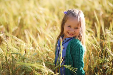 Genç anne yürüyerek buğday alanları içerisinde