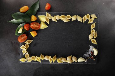 Siyah taş üzerine makarna kabukları. Allspi ile domates ve defne yaprağı