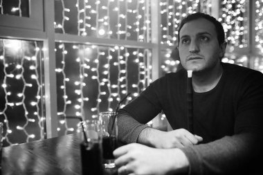 Bir gece kulübünde elinde nargile piposu ve sigara tutan bir adam. 