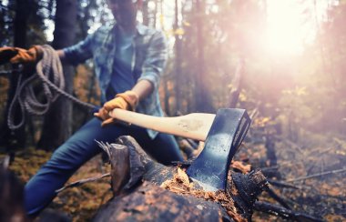 Male worker with an ax chopping a tree in the forest.