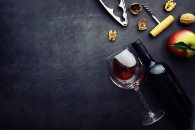 Şarap kadehi ve siyah şarap şişesi. Ceviz peyniri ve domates.