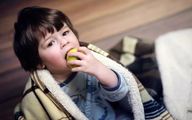 Küçük kıvırcık saçlı bir çocuğun portresi. Halıya sarılmış bir çocuk.