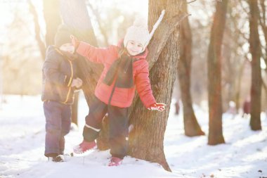 Kış parkında oynayan kalın elbiseli şirin çocuklar. 