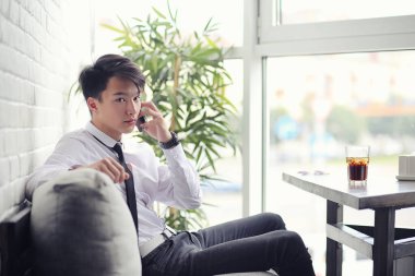 Genç Asyalı işadamı bir kafede bir ortak için bekliyor. Bu