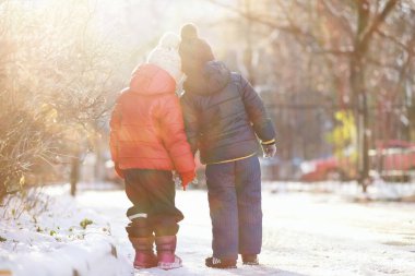Kış parkında oynayan kalın elbiseli şirin çocuklar. 