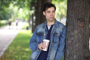 Genç bir adam öğle yemeği zamanında parkta yürür. Bir adam yürüyüşe çıktı. 