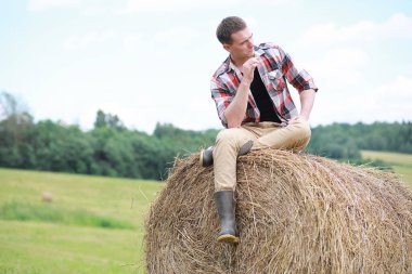 Gün batımında köy tarlasında çizmeli genç bir adam.
