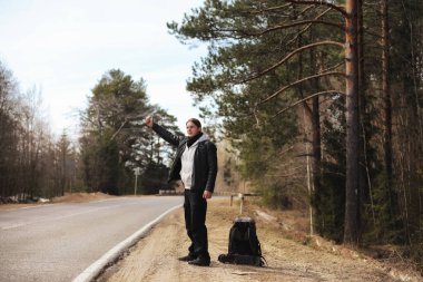 Genç bir adam ülke çapında otostop. Adam çalışıyor
