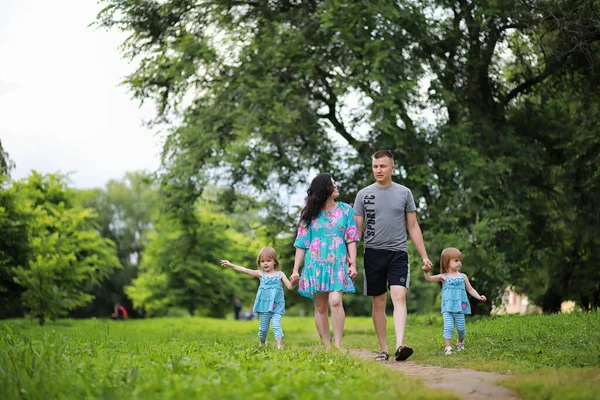 Family with two daughters twins for a walk in the park