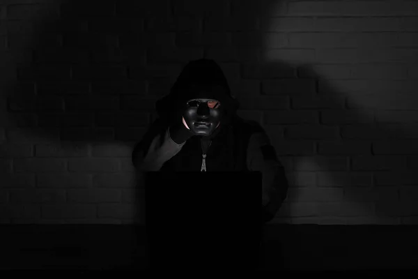 Hacker em máscara preta e capuz na mesa — Fotografia de Stock