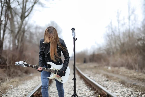 Una chica músico de rock en una chaqueta de cuero con una guitarra — Foto de Stock