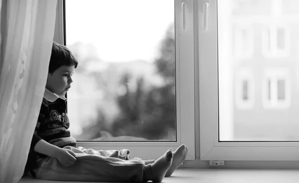 Anak kecil itu sedang membaca buku. Anak itu duduk di jendela — Stok Foto