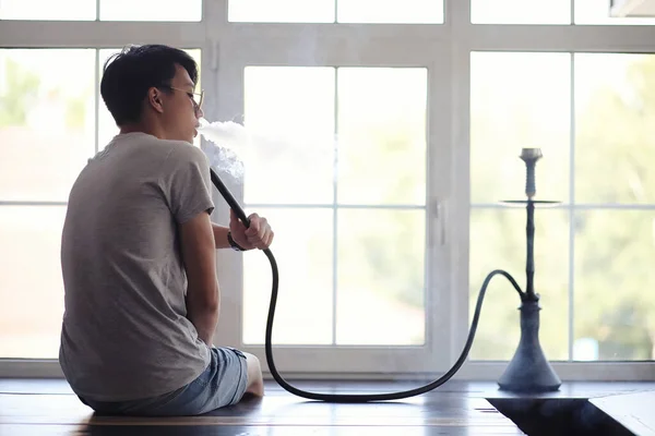 Asiatischer Mann raucht eine Wasserpfeife am Fenster — Stockfoto