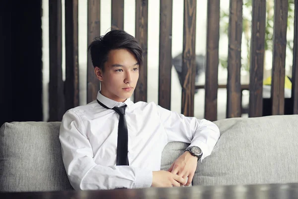 Un joven empresario asiático está esperando a un socio en un café. Bu. —  Fotos de Stock