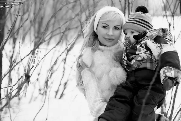 一个年轻的母亲走在一个冬天的一天, 怀里抱着一个孩子。 — 图库照片