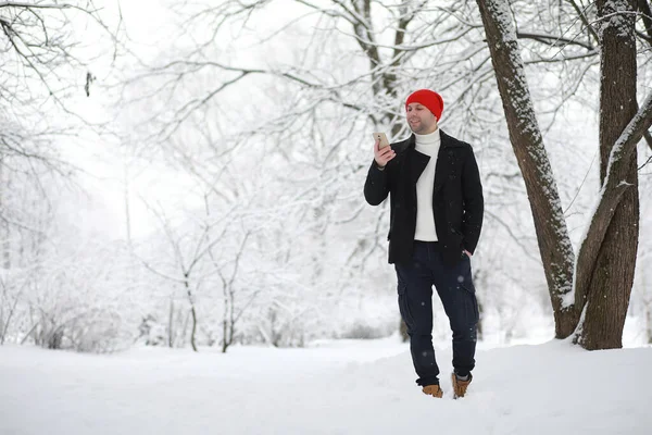 Un hombre en un paseo por el parque. Joven con en el invierno snowfa — Foto de Stock