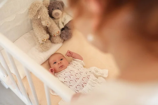 Newborn cute baby lies in the crib and looking mother — Stock Photo, Image