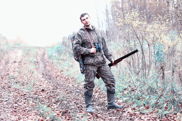 A man in camouflage and with a hunting rifle in a forest on a sp — Stock Photo, Image