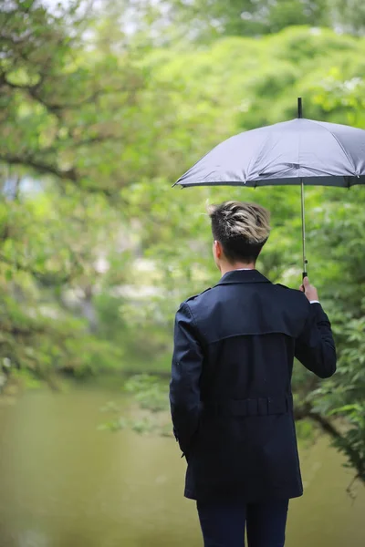 Spring rainy weather and a young man with an umbrella — Stock Photo, Image