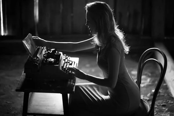 A girl prints on an old typewriter — Stock Photo, Image