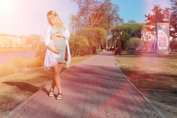 Une fille enceinte en promenade dans le parc. Fille avec un ventre dans le ci — Photo