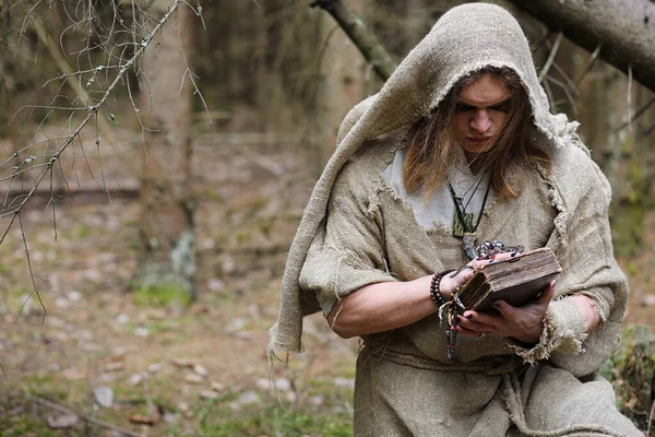 Un uomo con una tonaca trascorre un rituale in una foresta oscura — Foto Stock