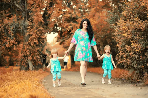 Мама с двумя дочерьми близнецы осень — стоковое фото