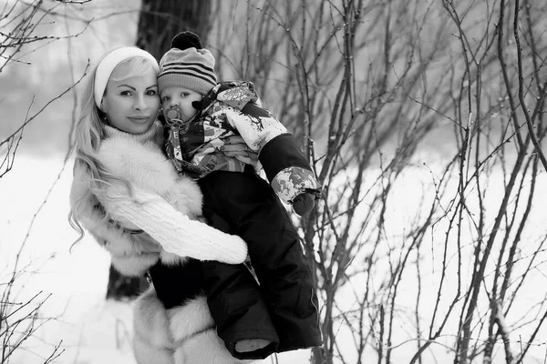 Una joven madre camina en un día de invierno con un bebé en sus brazos — Foto de Stock