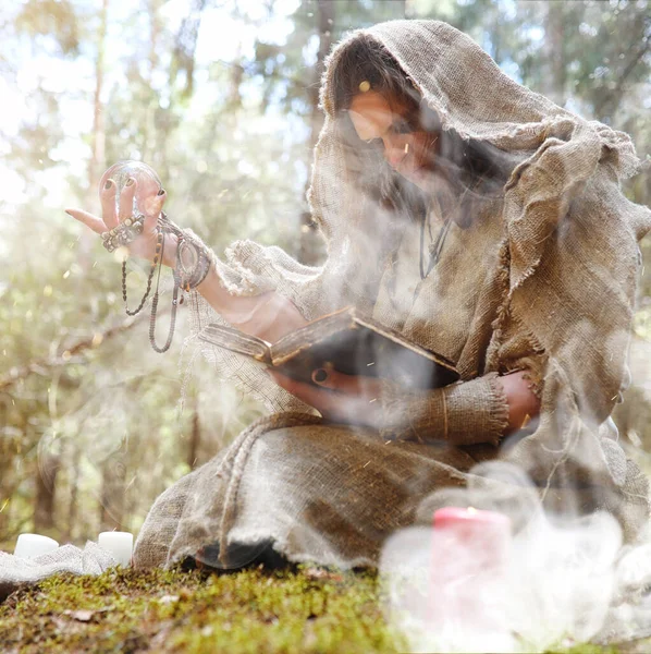 Un hombre en una sotana pasa un ritual en un bosque oscuro —  Fotos de Stock